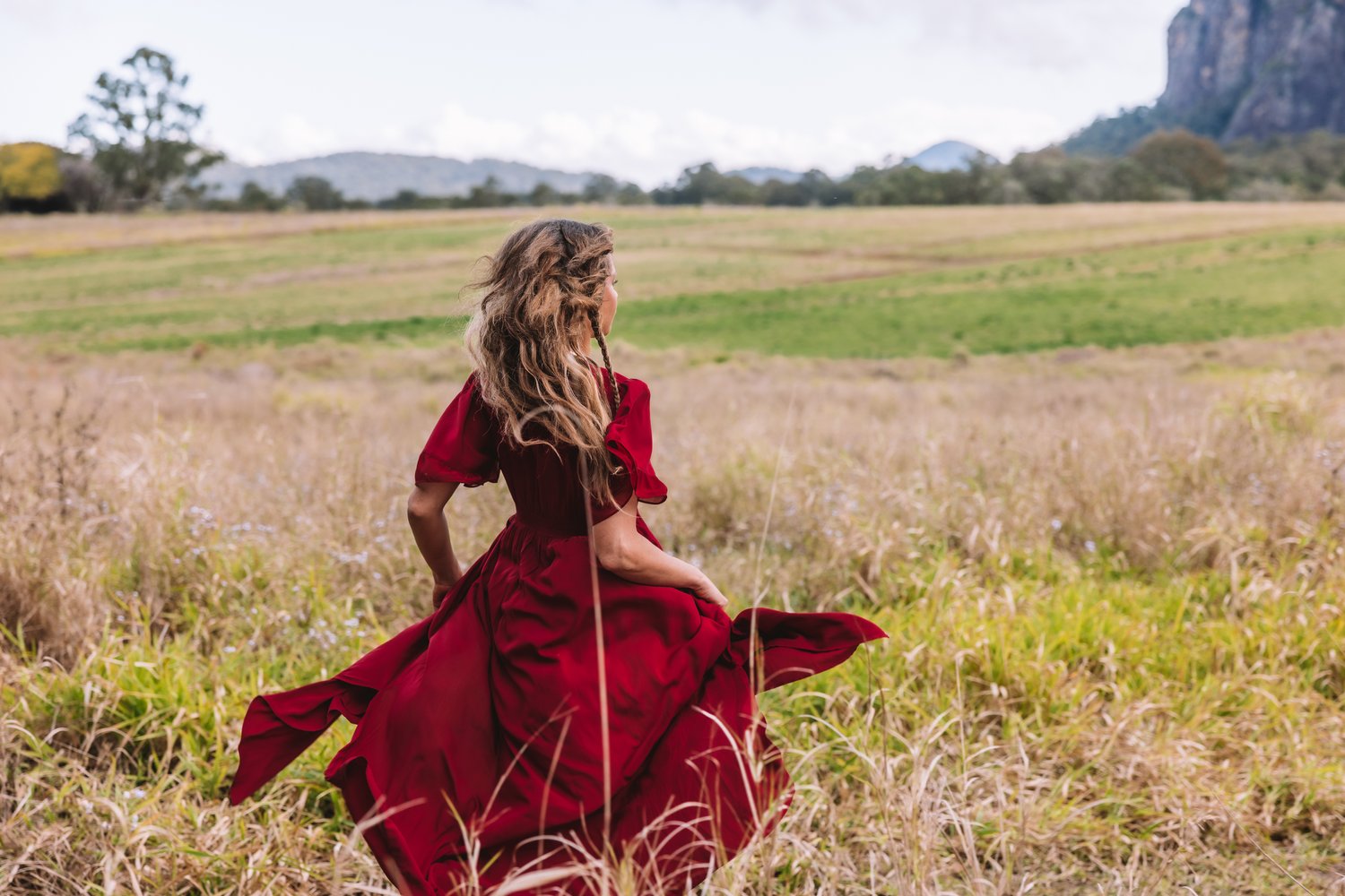 Women in red dress running in field 